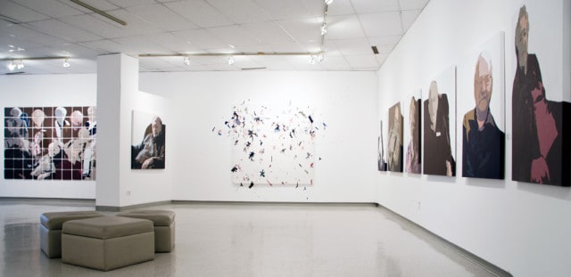 This wide-angle view of the Snelgrove Gallery features Donna Bilyk’s individual portraits, right, and a group painting, far left. 