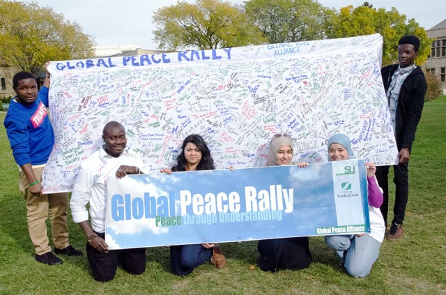 David Ogunkanmi (front left) and members of the Global Peace Alliance pose with the rally’s banner that garnered over 400 signatures.