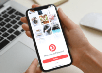 Woman holding iPhone 11 with Pinterest app on screen at table, closeup| Africa Images | Canva Pro