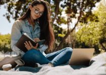 Young woman studying sitting outdoors | Jacob Lund | Canva Pro