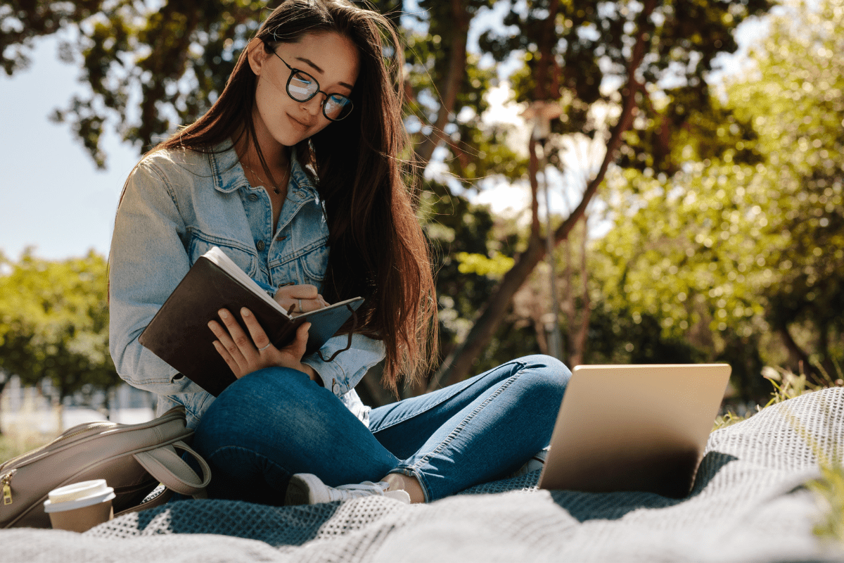 Young woman studying sitting outdoors | Jacob Lund | Canva Pro