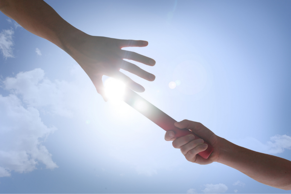 Hands passing a red baton under a clear sky | Aflo Images | Canva Pro