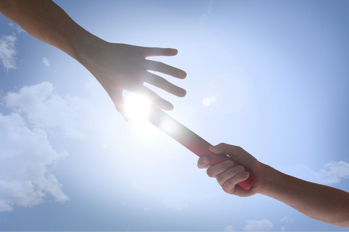 Hands passing a red baton under a clear sky | Aflo Images | Canva Pro