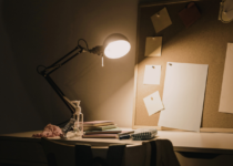 Focused workspace with desk lamp illuminating study materials | Canva Pro