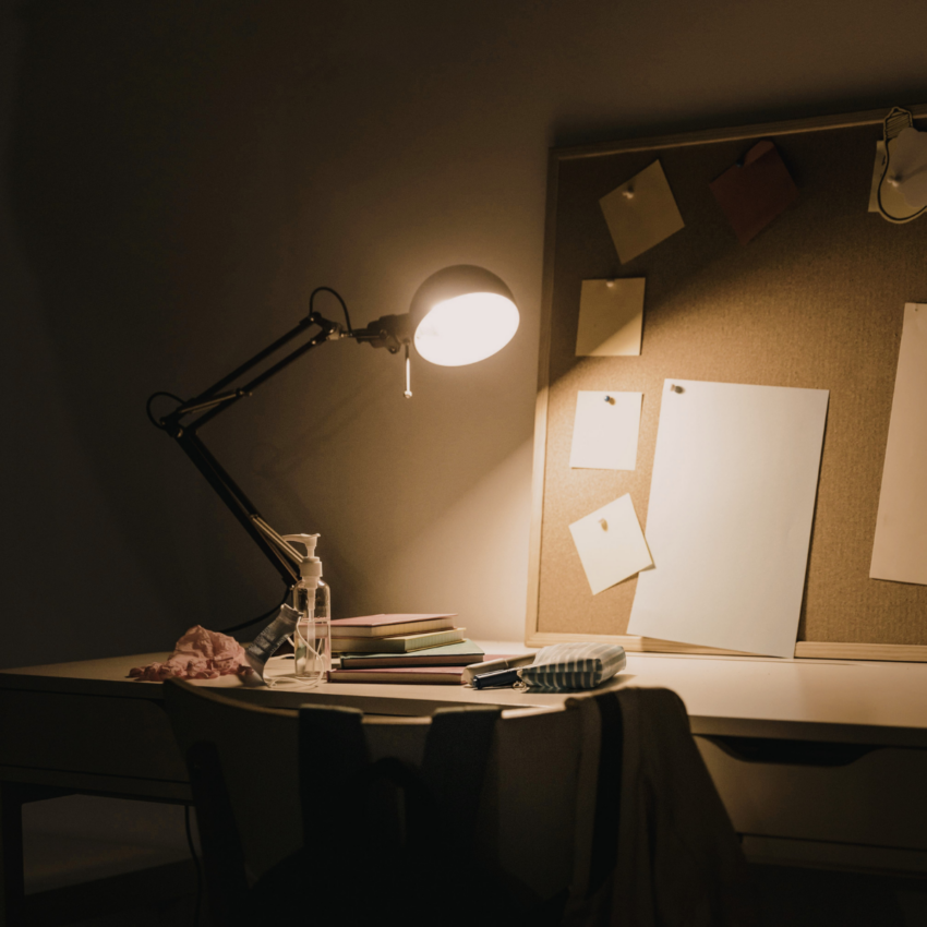 Focused workspace with desk lamp illuminating study materials | Canva Pro