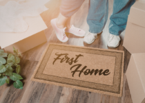 Couple standing on first home doormat | Canva Pro