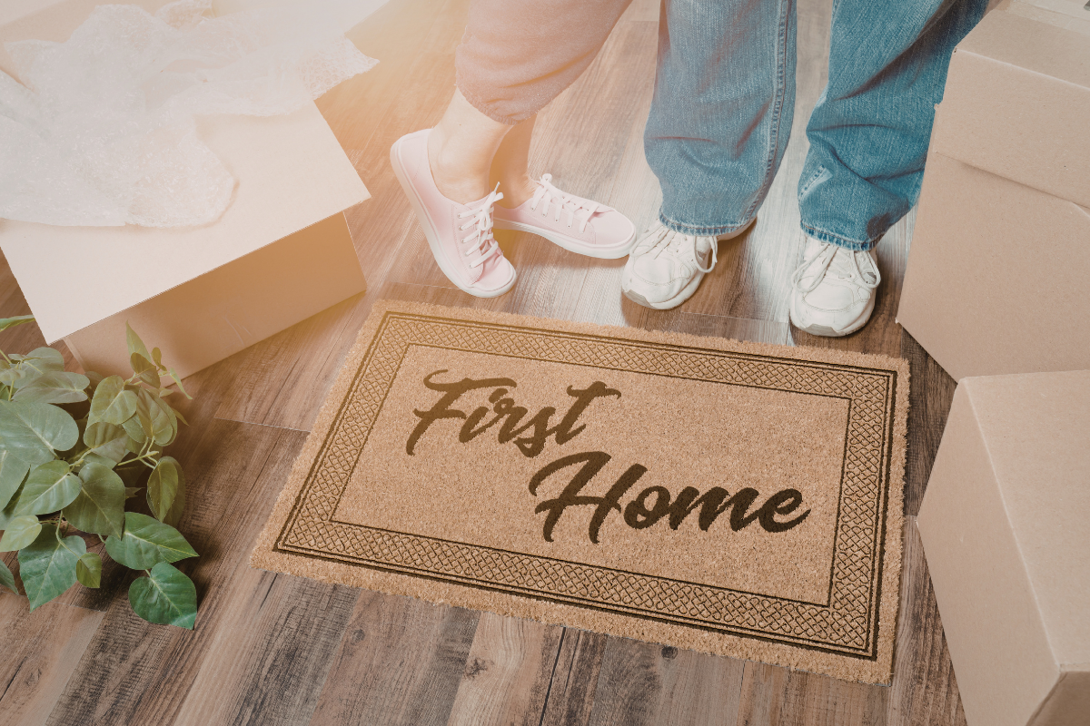 Couple standing on first home doormat | Canva Pro