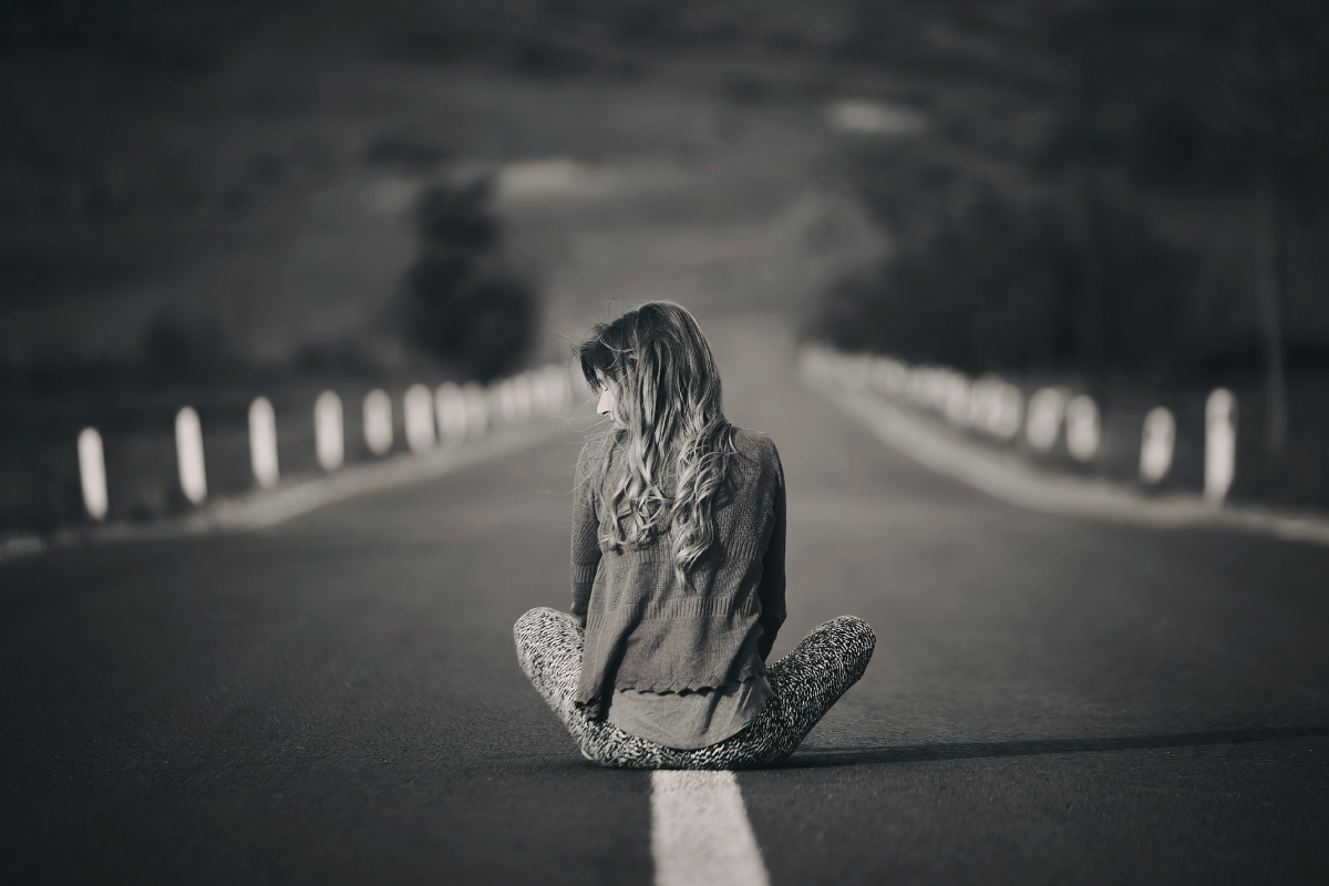Woman sitting alone on an empty road | Elisabeta Dirjan’s Images| Canva Pro