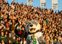 Howler stands in front of a packed crowd during the USask Homecoming football game| USask